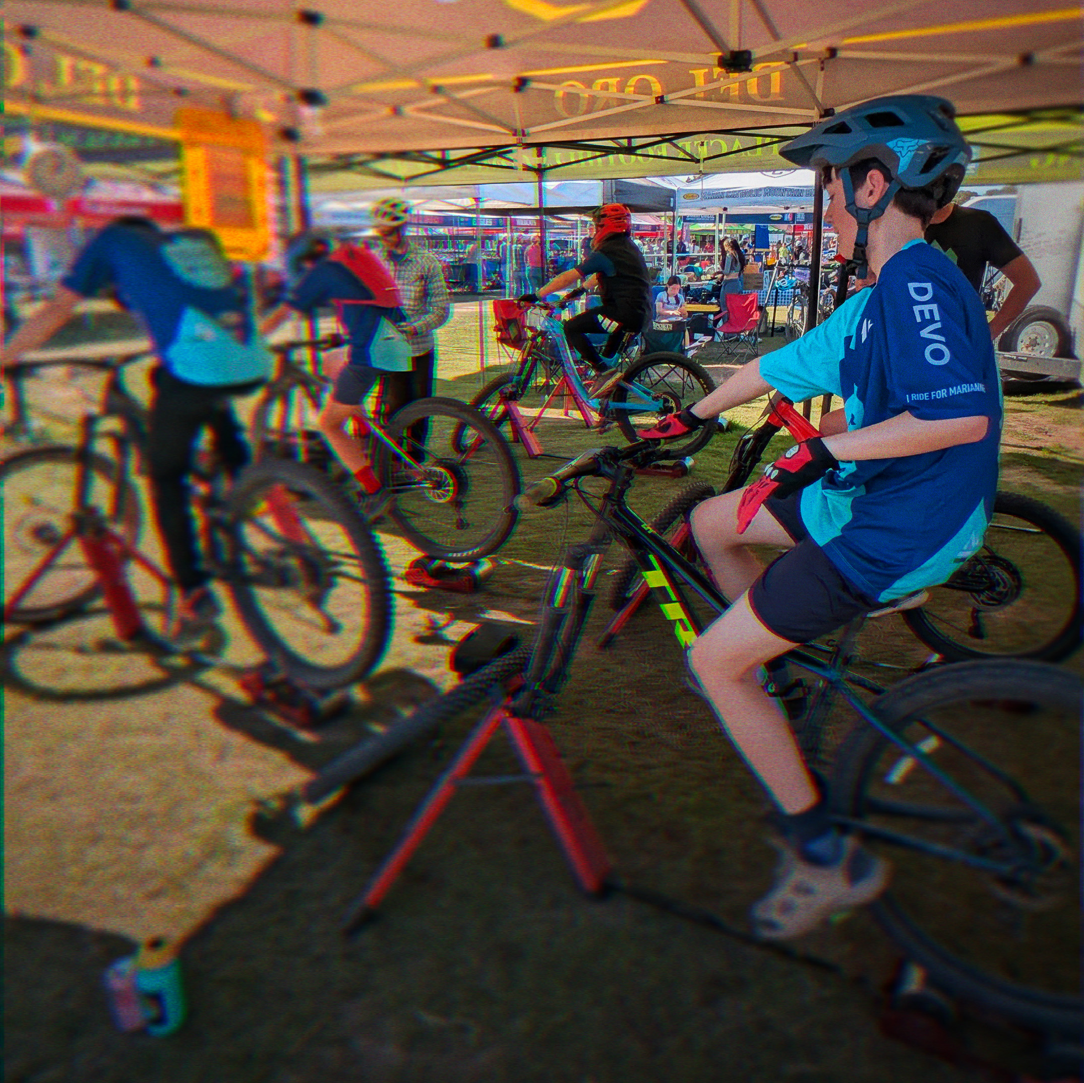 Five middle school mountain bike riders warm up on rollers before a race.